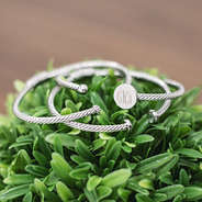 silver monogrammed bangles on green plant