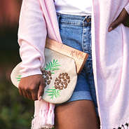 close up of monogrammed pineapple clutch with monogrammed fringe cardigan