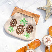 monogrammed pineapple clutch with monogrammed embroidered sandals on beach