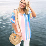 girl with monogrammed bamboo handbag on shoulder in front of water