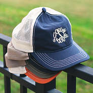 monogrammed snapback baseball hats stacked on fence with grass in background