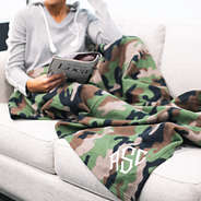 girl on couch in pjs covered up with monogrammed camo fleece blanket