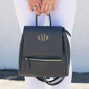 girl holding monogrammed mini backpack by handle