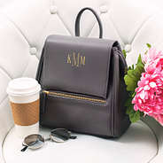 charcoal gray foil stamped mini backpack sitting in chair with flowers and coffee