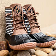 black striped monogrammed duck boots on rocks