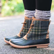 side view of monogrammed plaid duck boots on asphalt