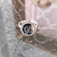 sterling silver monogrammed nala ring sitting on glass tabletop