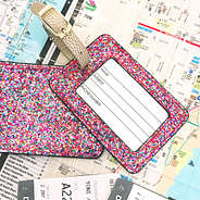 confetti glitter luggage tag front and back laying on a map