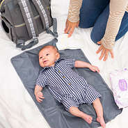 baby laying on diaper bag pad