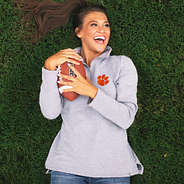 brunette laying in grass holding football and wearing clemson pullover sweatshirt
