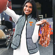 girl wearing tennessee herringbone vest and holding football and pom pom