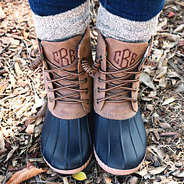 monogrammed duck boots in navy with socks standing on leaves