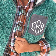 teal monogrammed sherpa jacket with orange and teal plaid underneath