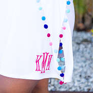 detail of monogrammed pom pom cover up in white