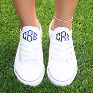 girl wearing monogrammed white canvas sneakers on grass