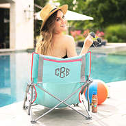 girl sitting in monogrammed beach chair by the pool
