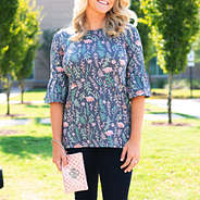 girl in floral top holding monogrammed rose gold wristlet