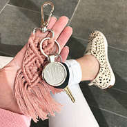 blush macrame keychain in hand with spotted sneakers