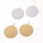silver and gold monogrammed brushed earrings on fur