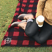 girl sitting on monogrammed buffalo plaid blanket outside