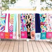 group of monogrammed beach towels on porch railing