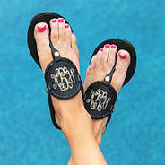 black monogrammed flip flops with pool in background