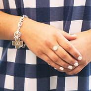 silver monogrammed cross pendant bracelet on wrist with gingham dress