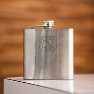 silver flask sitting with wood behind