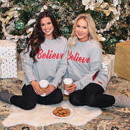 girls in matching believe sweatshirts with cookies by christmas tree