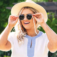 girl holding sunglasses with shell strap around neck