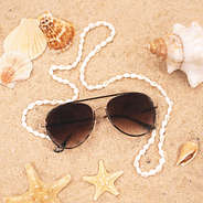 seashell sunglasses strap on aviator sunglasses laying in sand