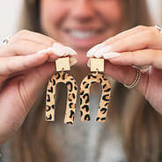 girl holding leopard horseshoe earrings
