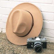 tan felt fedora against white brick wall