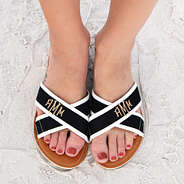 monogrammed criss cross sandals on feet at the beach