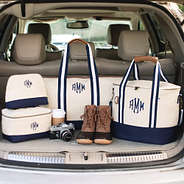 navy and canvas travel bags packed in trunk with duck boots and coffee