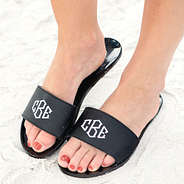 black monogrammed jelly slides on feet on the beach