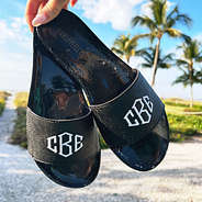 holding black monogrammed jelly slides