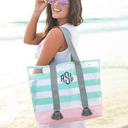 monogrammed clear fringe beach tote on shoulder at beach