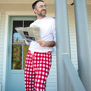 dad wearing christmas pajama pants reading the newspaper
