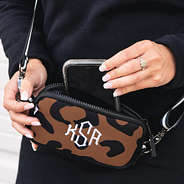 phone in pocket of monogrammed neoprene crossbody in leopard