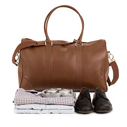 leather Monogrammed Weekender sitting behind mens clothes and shoes