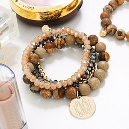 set of beaded bracelets in brown and gold with monogrammed charm