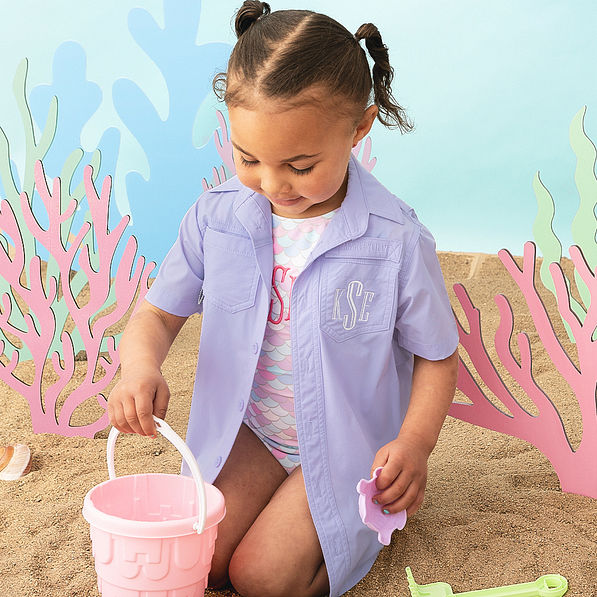 girl building sand castle with monogrammed lavender fishing shirt