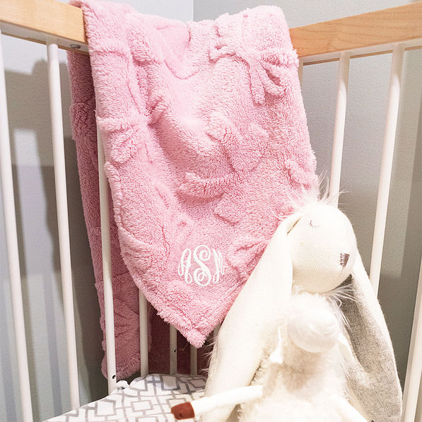 pink baby blanket in corner of crib