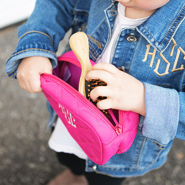 girl taking hairbrush out of kids quilted cosmetic case