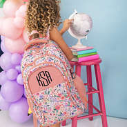 girl looking at globe with monogrammed coral floral backpack