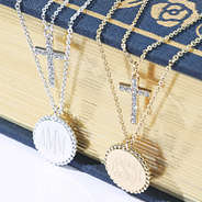 close up of monogrammed kids cross necklace in gold and silver on bible