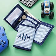 monogrammed wallet in navy seersucker on green background with toys