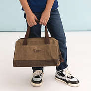 dark brown kids waxed canvas overnight bag in hands