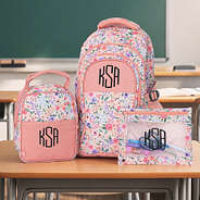 coral floral monogrammed backpack lunch box and binder pouch on students desk in classroom